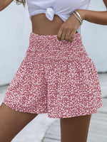 Person wearing a red floral skirt with a white top against a neutral background