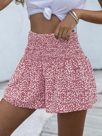 Person wearing a red floral skirt with a white top against a neutral background