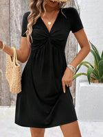 Woman wearing a black dress with a wooden wall and plant in the background