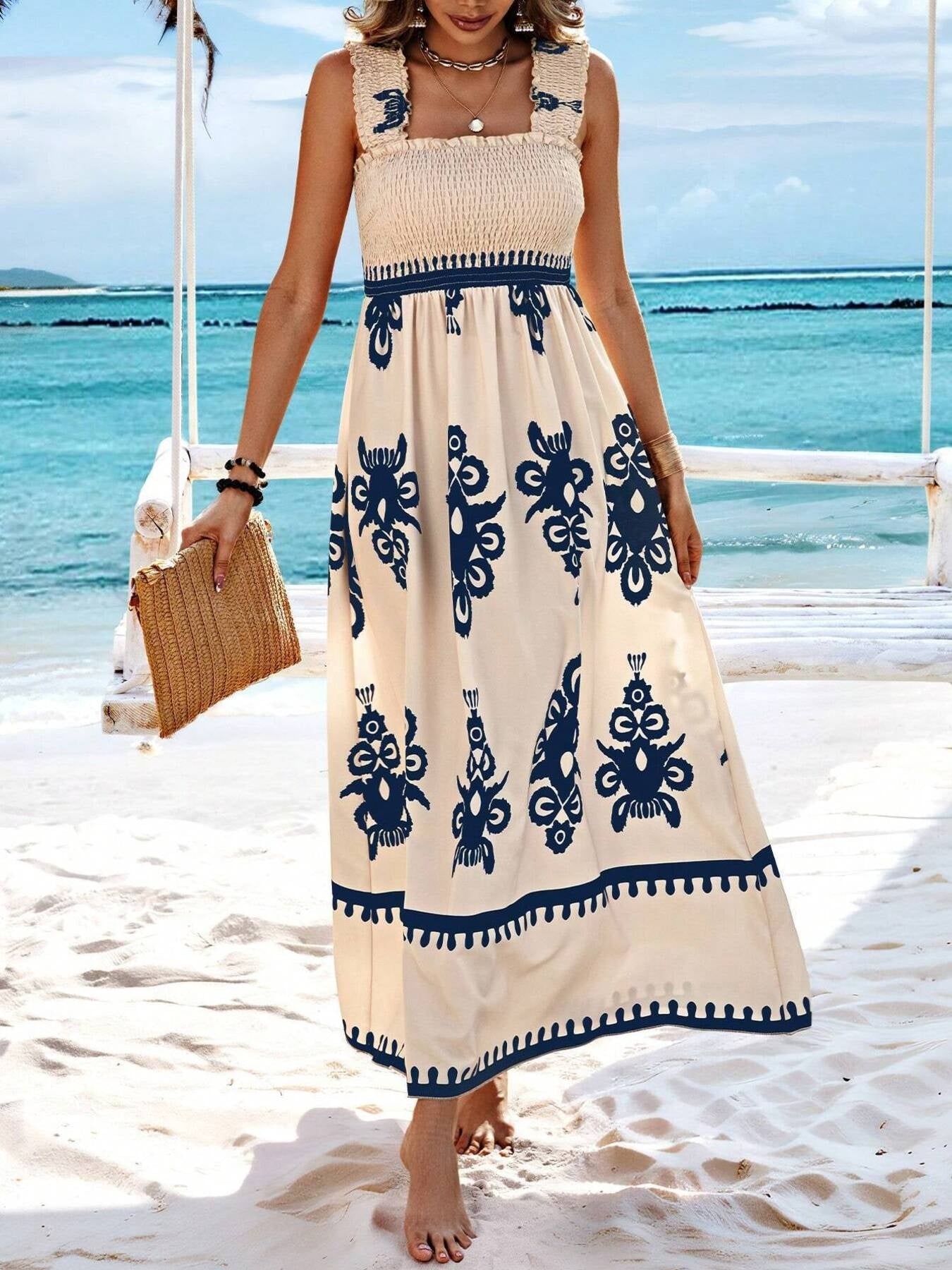 Woman in a long dress with blue patterns standing on a beach.