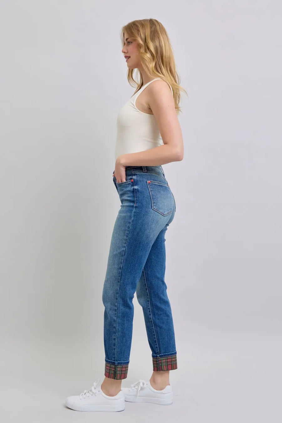 Woman wearing blue jeans with plaid cuffs on a white background