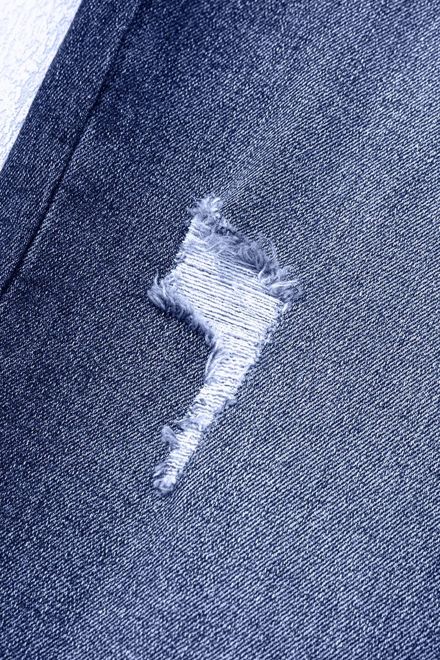 Close-up of a blue denim fabric with a distressed design.