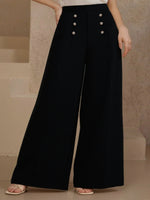 Black wide-leg pants with button details worn by a person against a neutral background