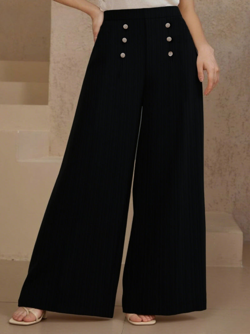 Black wide-leg pants with button details worn by a person against a neutral background