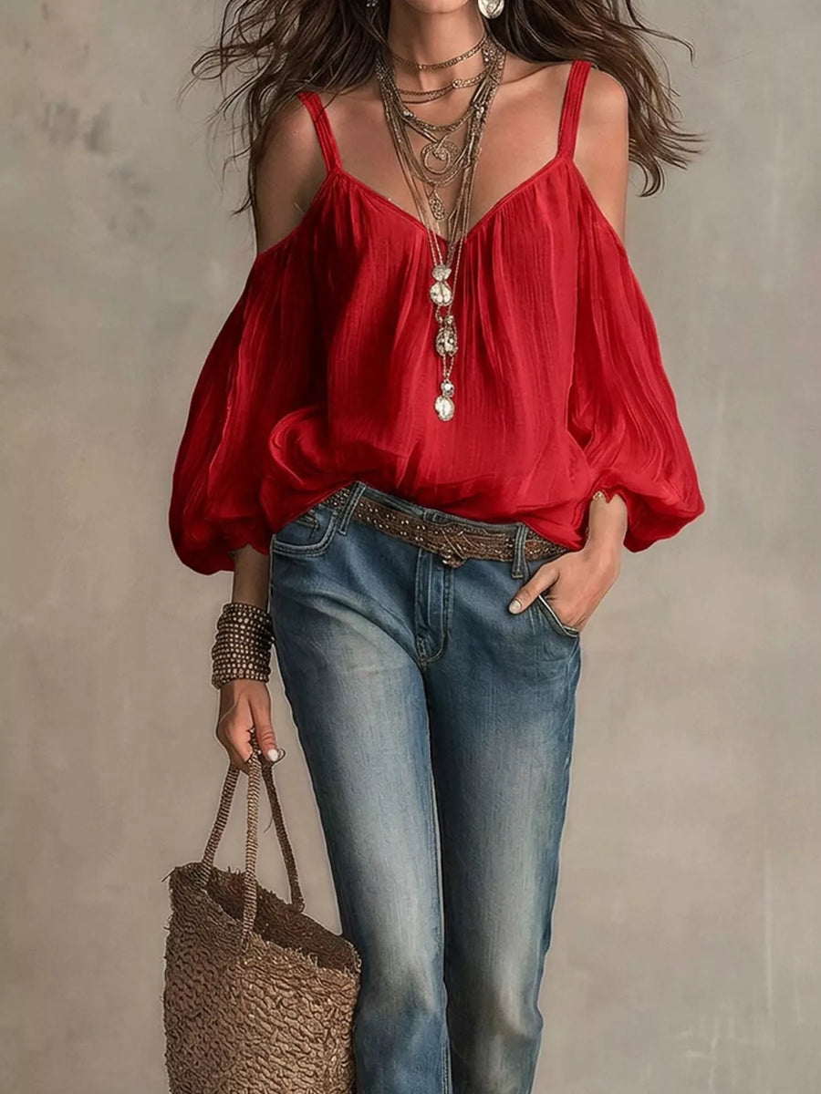 Woman wearing a red blouse and blue jeans, holding a woven bag against a neutral background