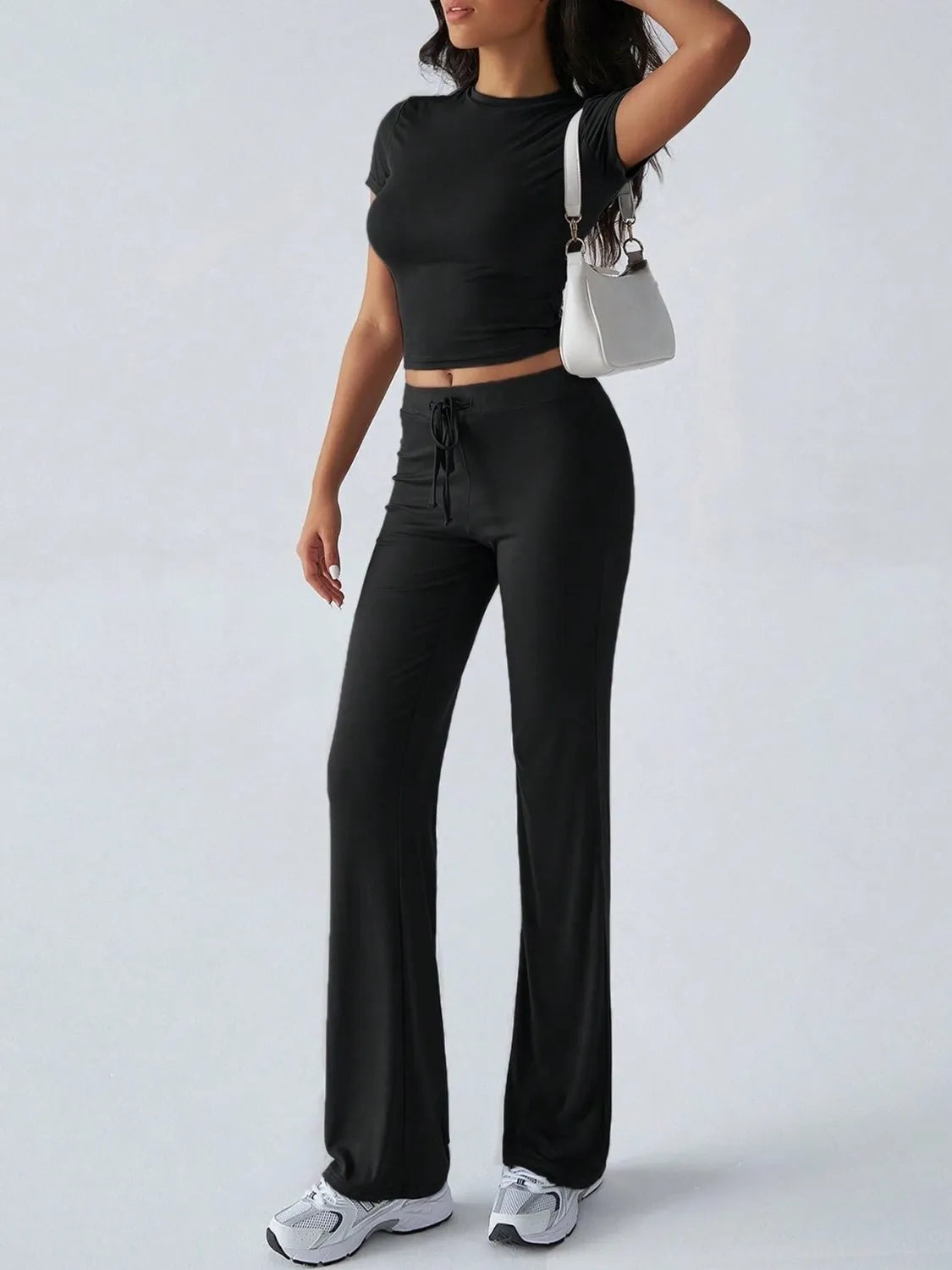 Person wearing a black outfit with wide-leg pants on a white background