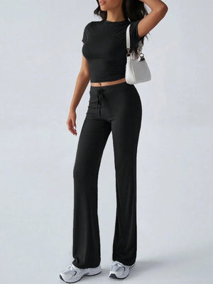 Person wearing a black outfit with wide-leg pants on a white background
