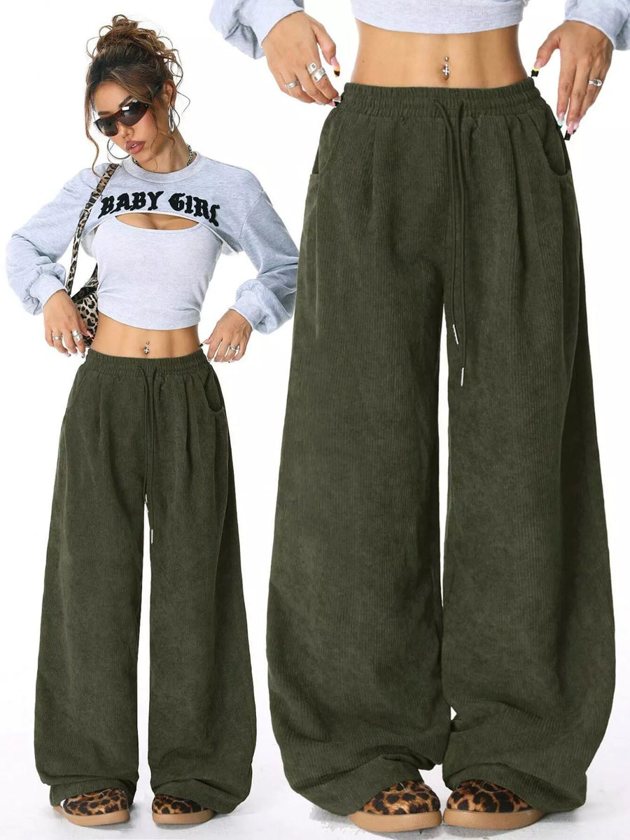 Woman wearing olive green wide-leg pants with a white crop top and leopard print sandals.