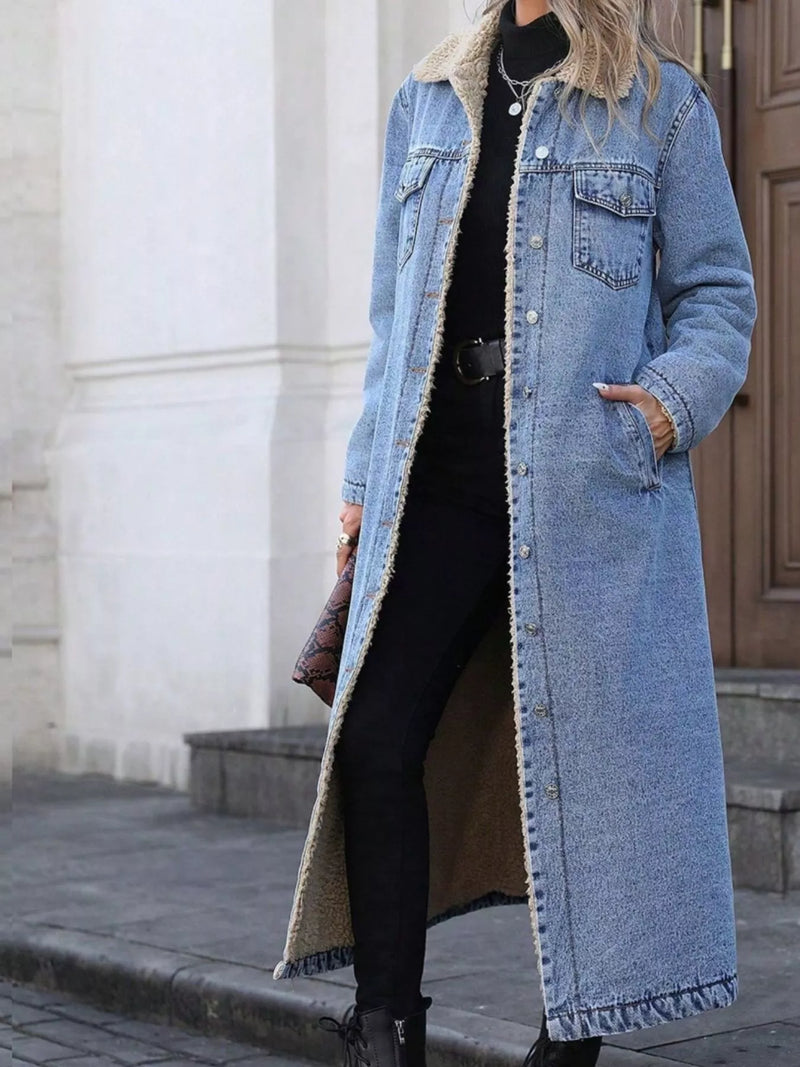 Person wearing a long denim coat with a blurred background