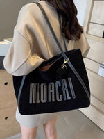 Person holding a black handbag with 'MOACHI' branding.