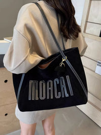 Person holding a black handbag with 'MOACHI' branding.