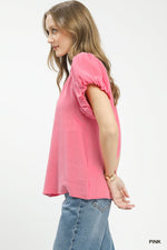 Woman wearing a pink blouse with puff sleeves on a white background