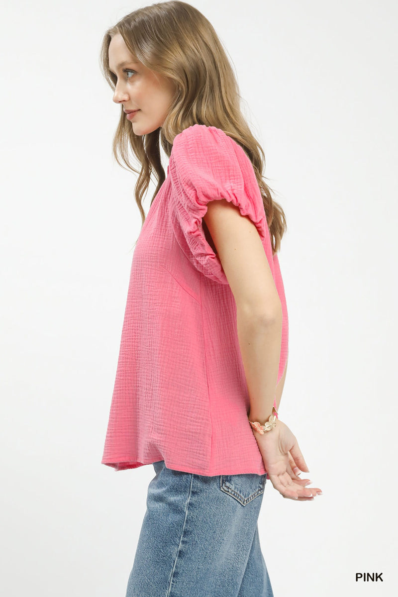 Woman wearing a pink blouse with puff sleeves on a white background