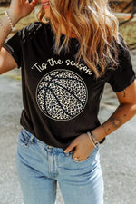 Person wearing a black t-shirt with a leopard print design and text, standing outdoors.