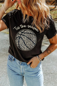 Person wearing a black t-shirt with a leopard print design and text, standing outdoors.