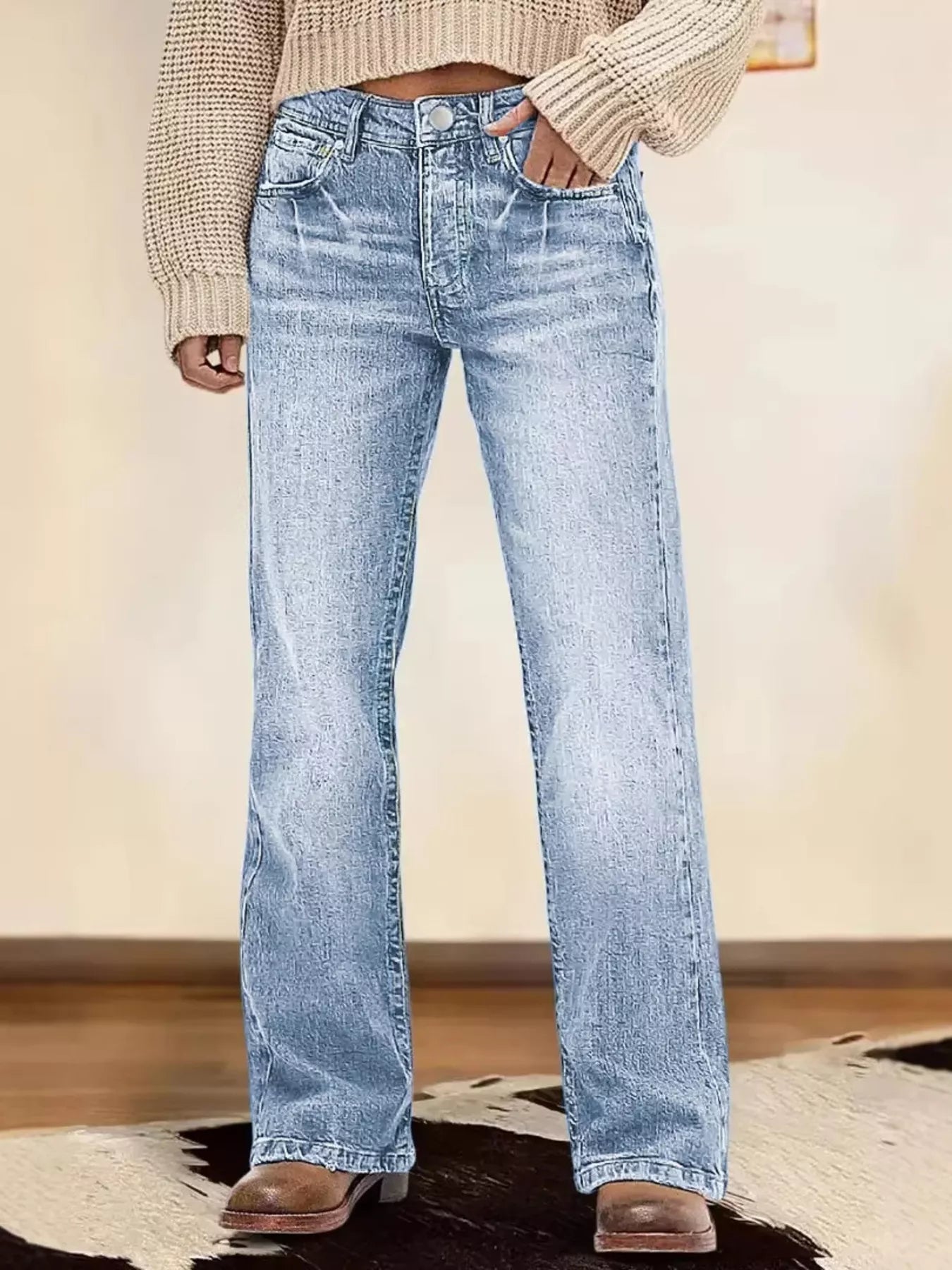 Person wearing light blue jeans and a beige sweater on a neutral background