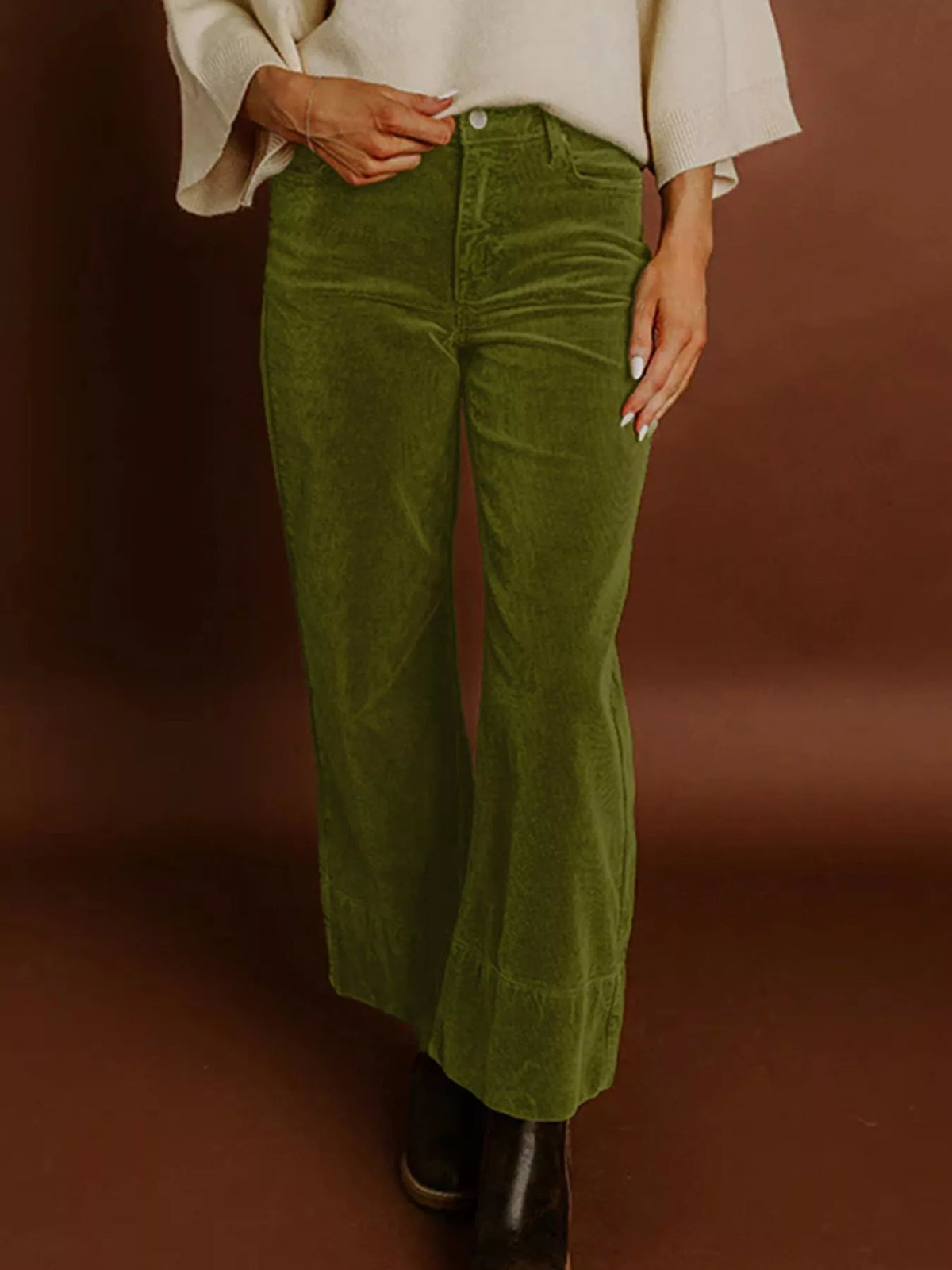 Person wearing green corduroy pants against a brown background