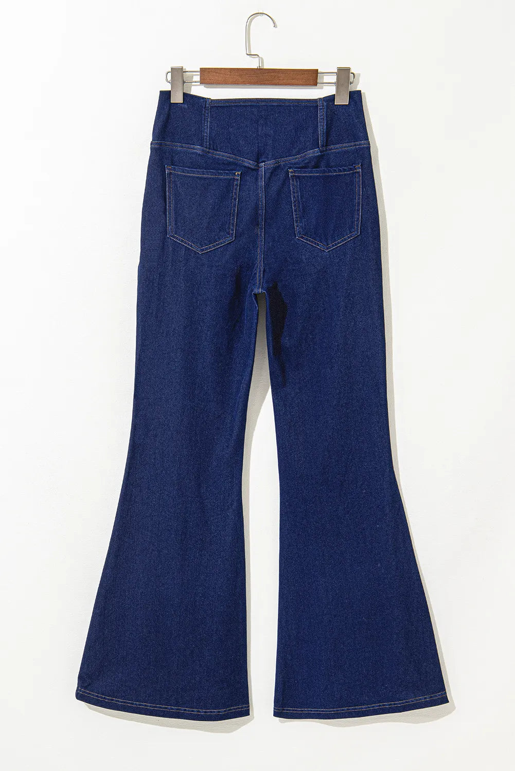 Blue flared jeans on a hanger against a white background