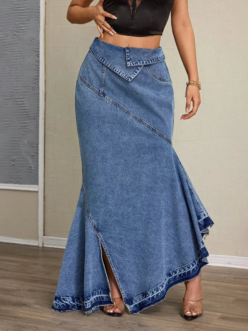 Person wearing a long blue denim skirt with a plain background