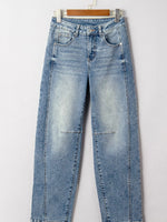 Blue jeans hanging on a wooden hanger against a white background