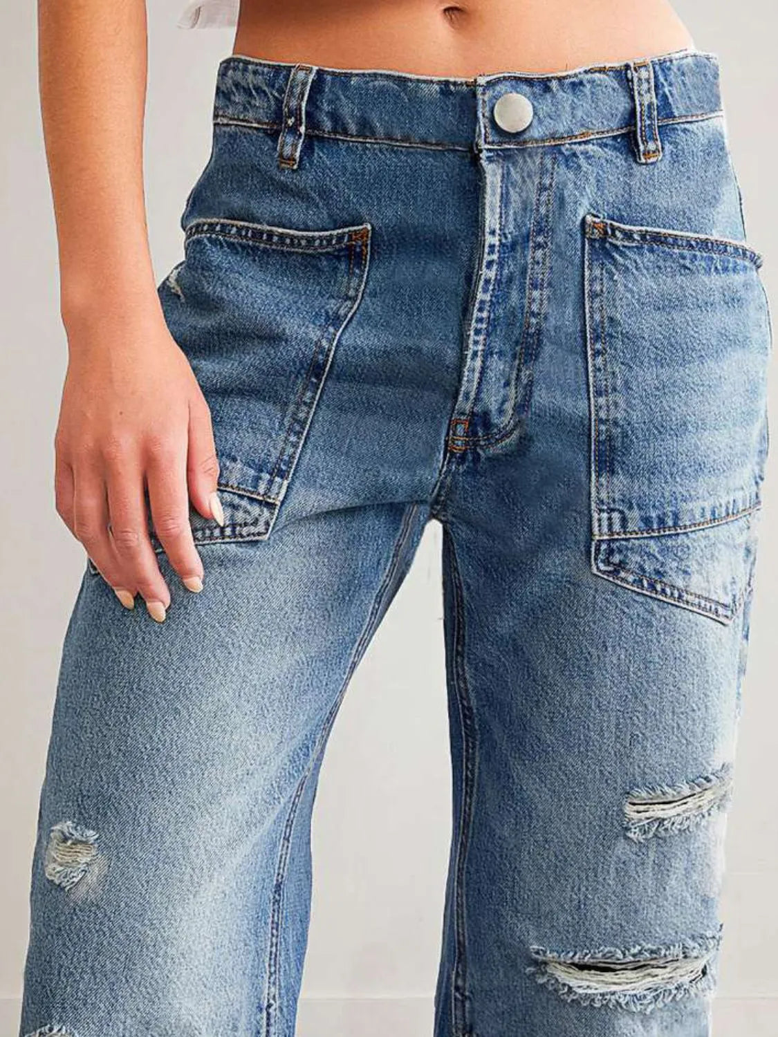 Close-up of distressed blue jeans on a plain background