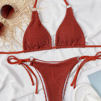 Red textured bikini set on a white surface with sunglasses and a hat.