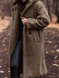 Person wearing a long brown coat in a forest setting