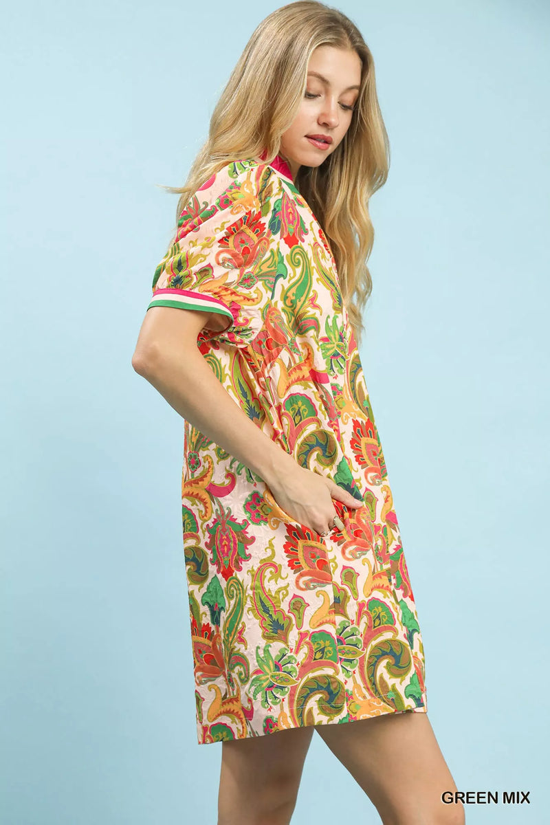 Woman wearing a colorful patterned dress against a light blue background
