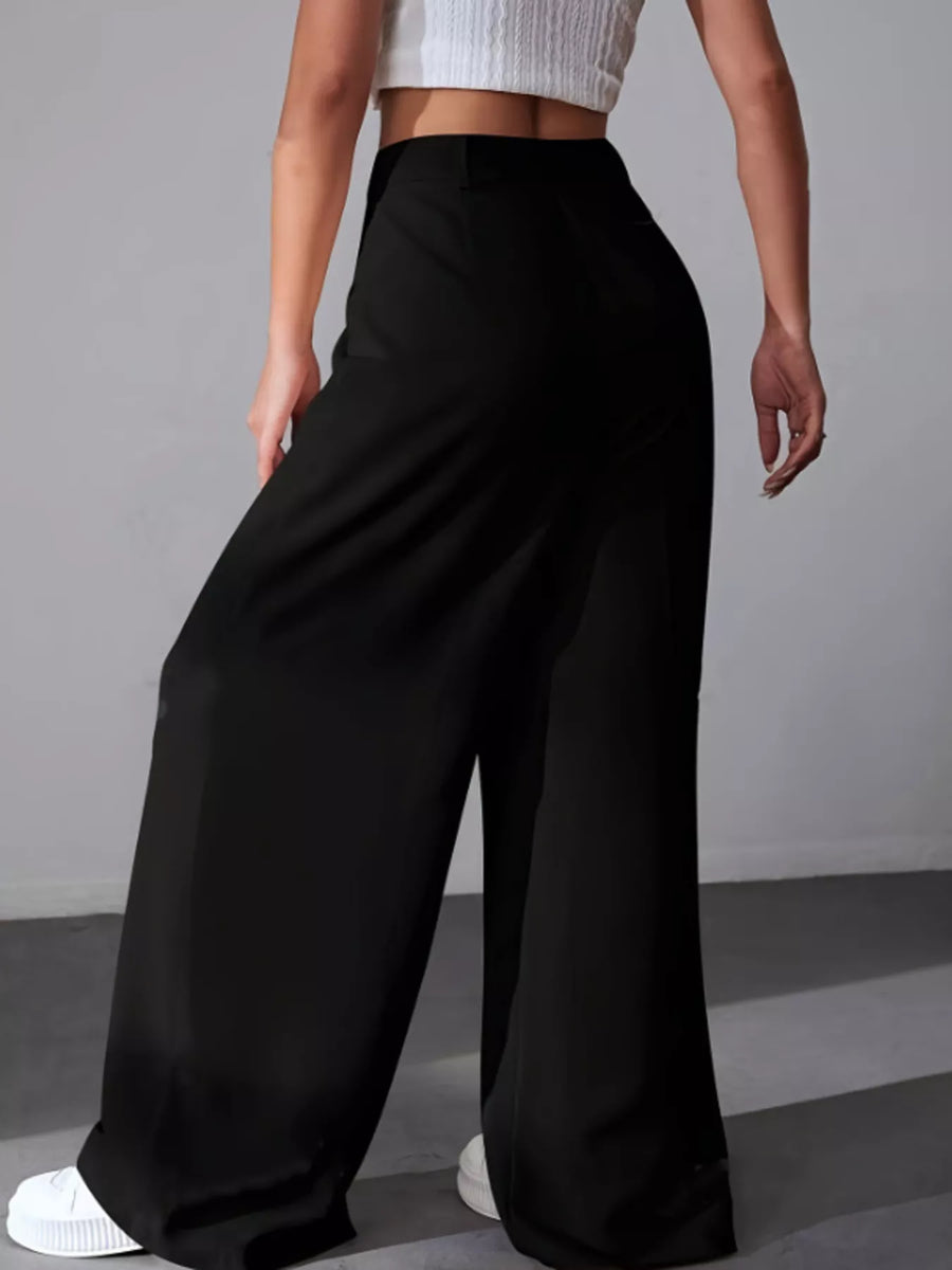 Person wearing black wide-leg pants on a gray background