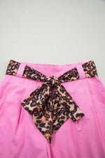 Pink skirt with a leopard print belt on a light gray background
