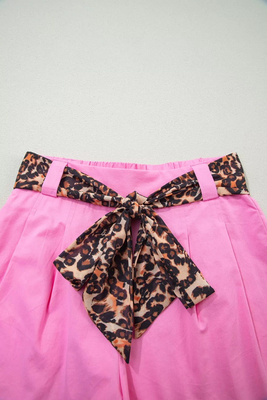 Pink skirt with a leopard print belt on a light gray background