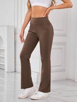 Person wearing brown high-waisted pants and white sneakers in a minimalistic setting