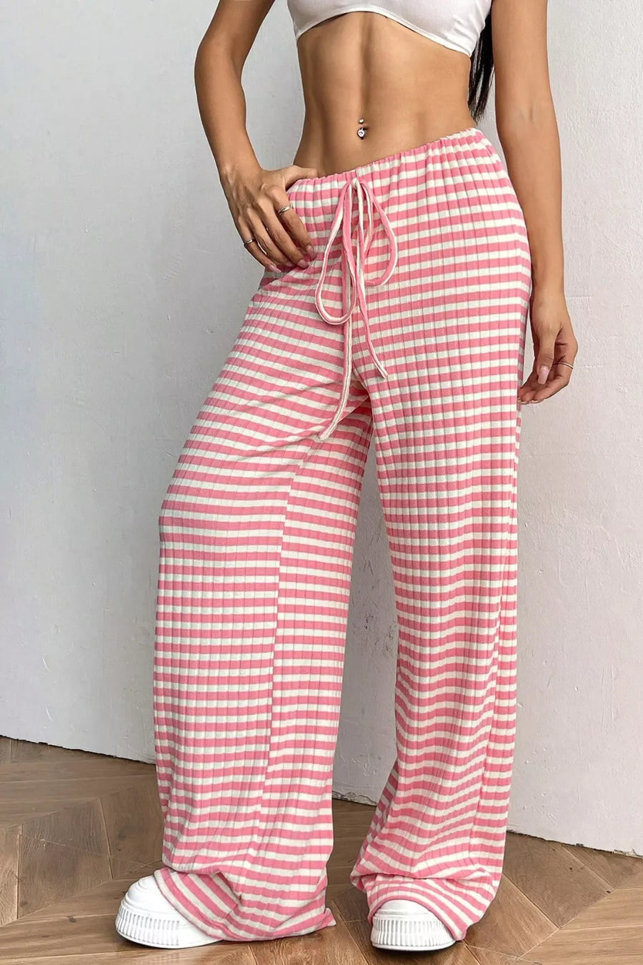 Person wearing pink and white striped pants on a plain background