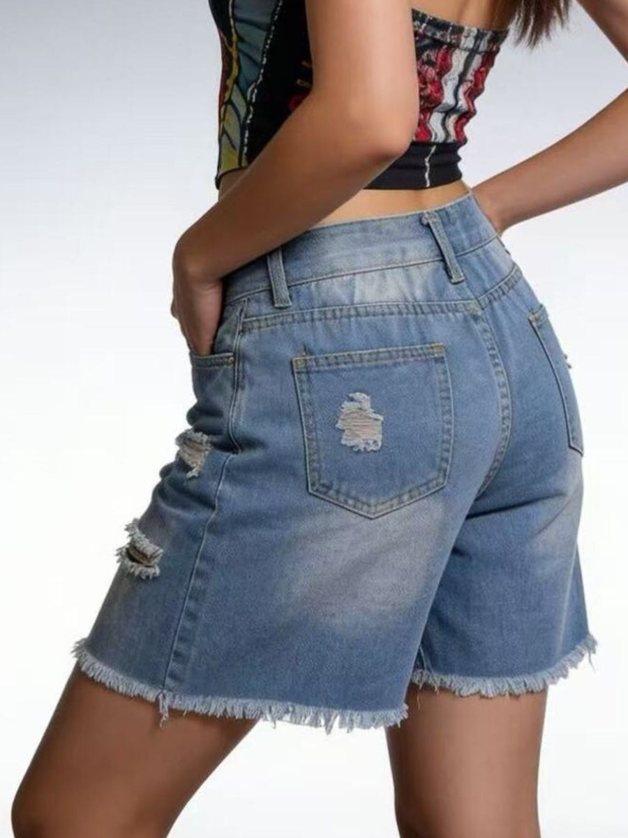Denim shorts worn by a person on a plain background