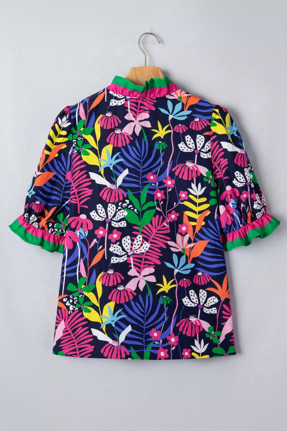 Colorful floral dress on a hanger against a gray background
