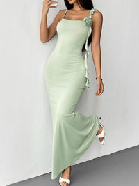 Woman wearing a light green dress with ruffled straps against a white background