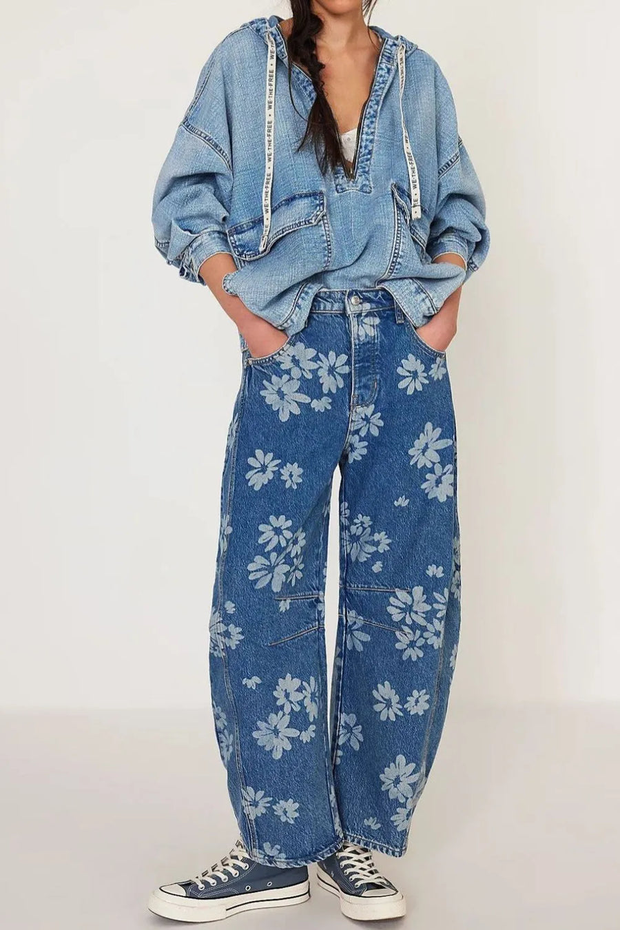 Person wearing a denim jacket and floral jeans on a white background