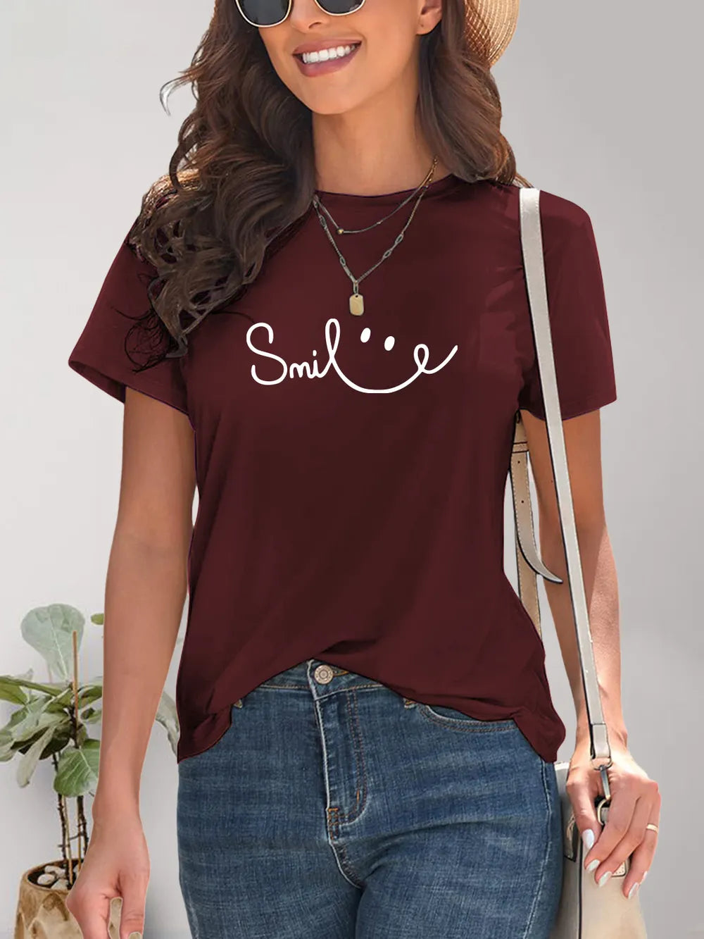 Woman wearing a maroon t-shirt with 'Smile' text and smiling.