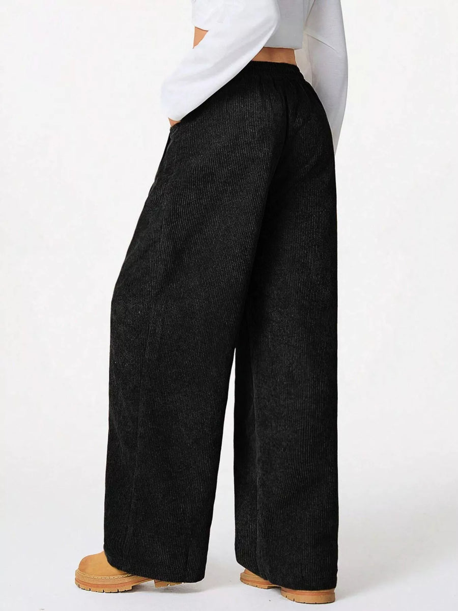 Person wearing black wide-leg pants on a white background
