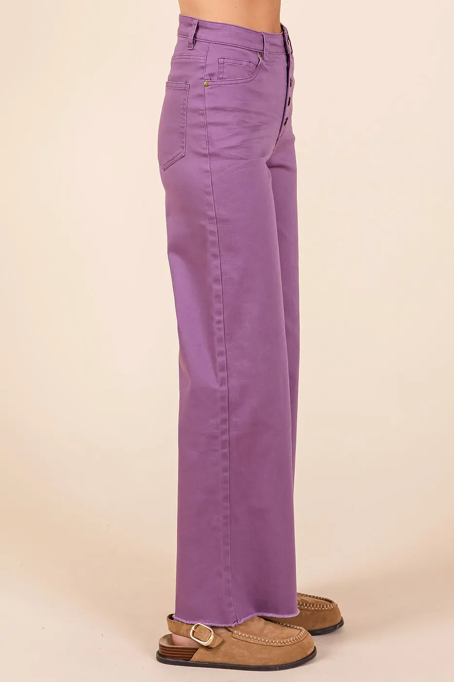 Purple pants worn by a person on a beige background