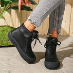 Person wearing black ankle boots with a casual outfit against a wooden fence background