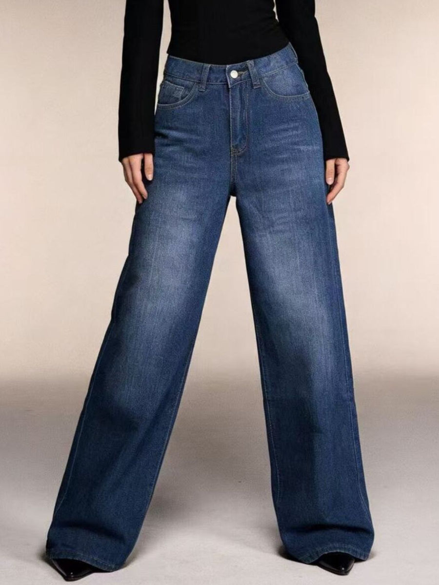 Blue jeans worn by a person on a plain background