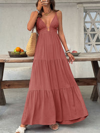 Woman in a long rust-colored dress standing outdoors near a wooden table.