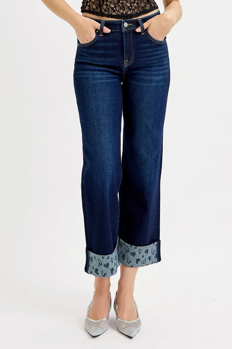 Person wearing blue jeans with floral cuffs on a white background