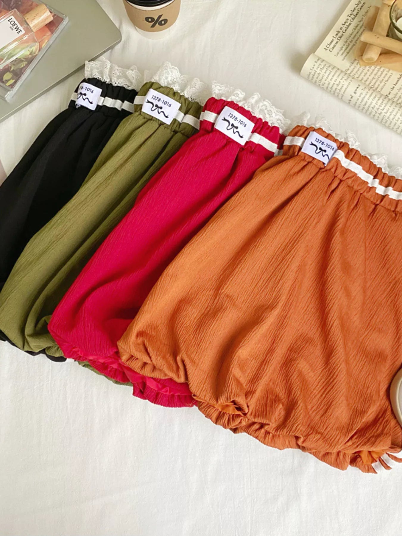 Four pairs of colorful bloomers on a white surface with a magazine and cup in the background.