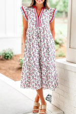 Woman wearing a floral dress with colorful trim in an outdoor setting