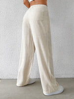 Person wearing beige wide-leg pants against a plain background