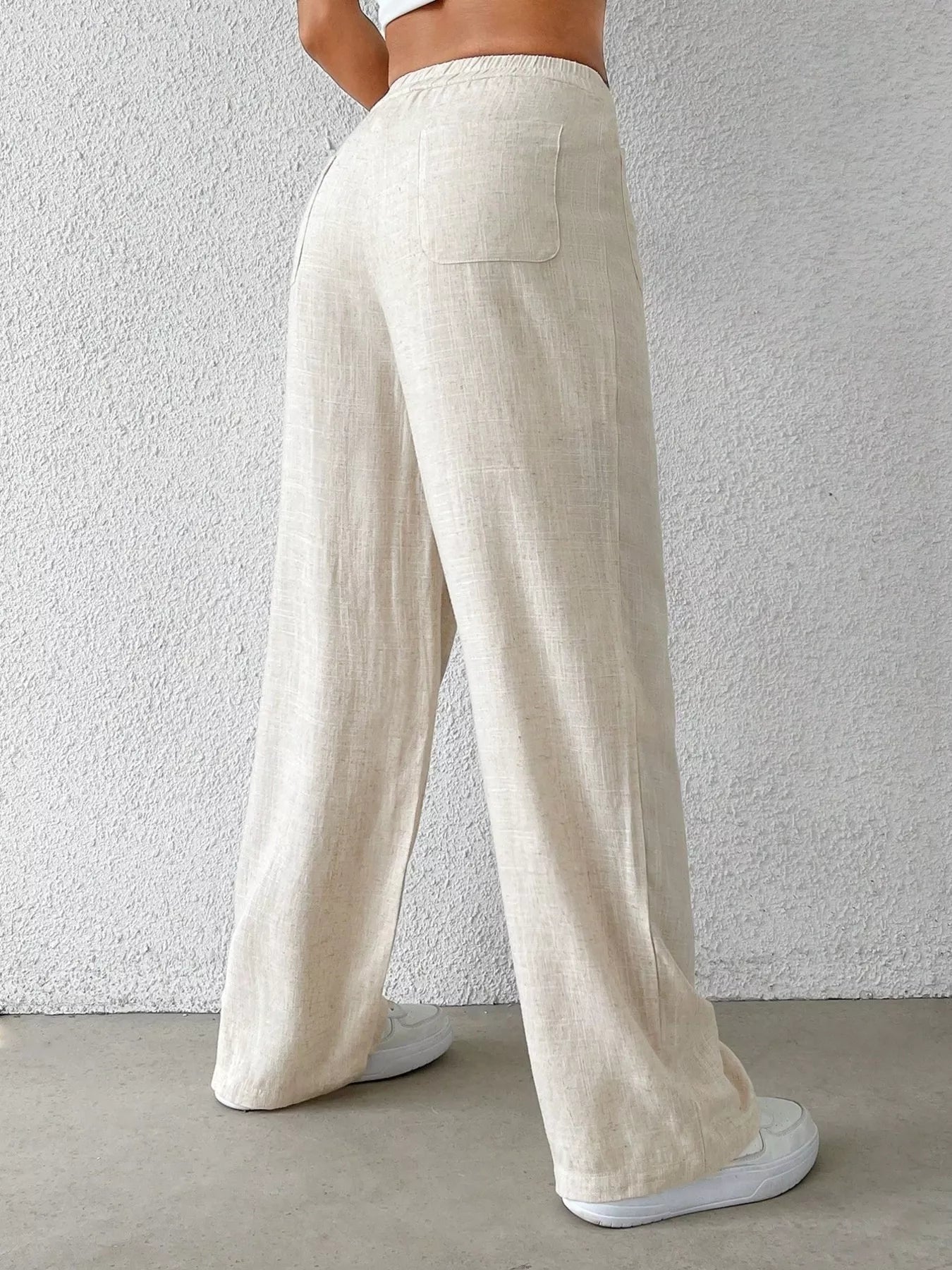 Person wearing beige wide-leg pants against a plain background