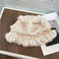 Pink knitted hat with white fur trim on a wooden surface