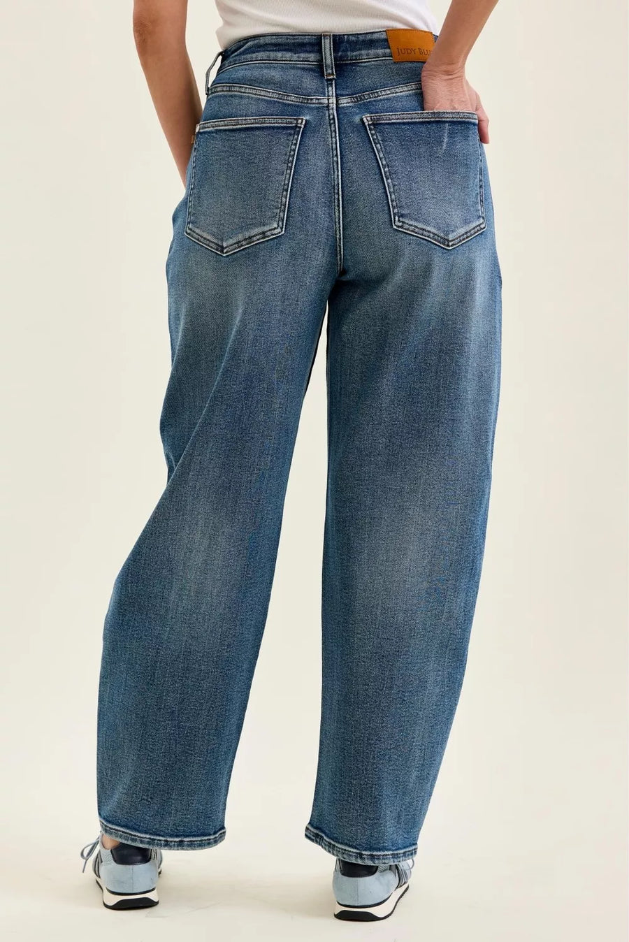 Person wearing blue jeans on a plain background
